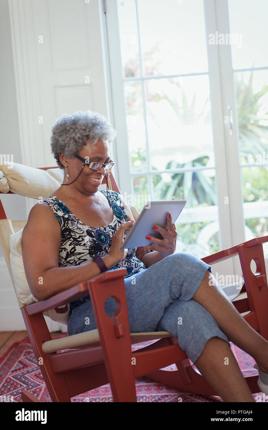 Ältere Frau mit digitalen Tablette im Schaukelstuhl Stockfoto