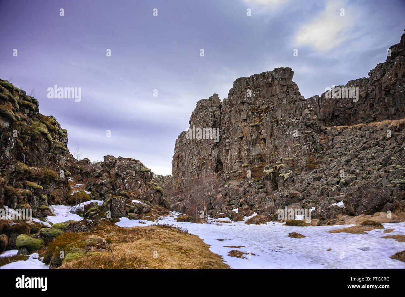 Thingvellir Rift Valley, den Nationalpark Thingvellir, Island. Rocky Risse entlang der Kontinentaldrift, bewölkte Himmel und Schnee im Vordergrund Stockfoto