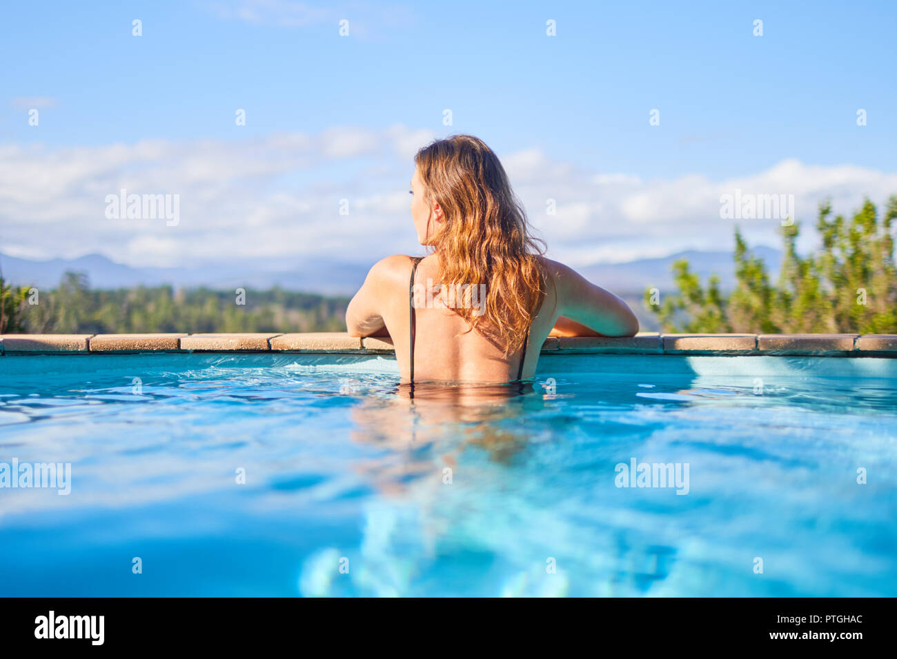 Heitere Frau im sonnigen Swimmingpool Stockfoto