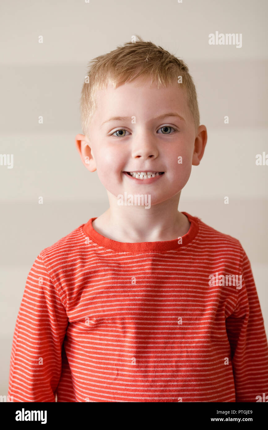 Kleiner Junge in einem rot gestreiften T-Shirt lächelnd, während die Kamera für ein Portrait. Stockfoto