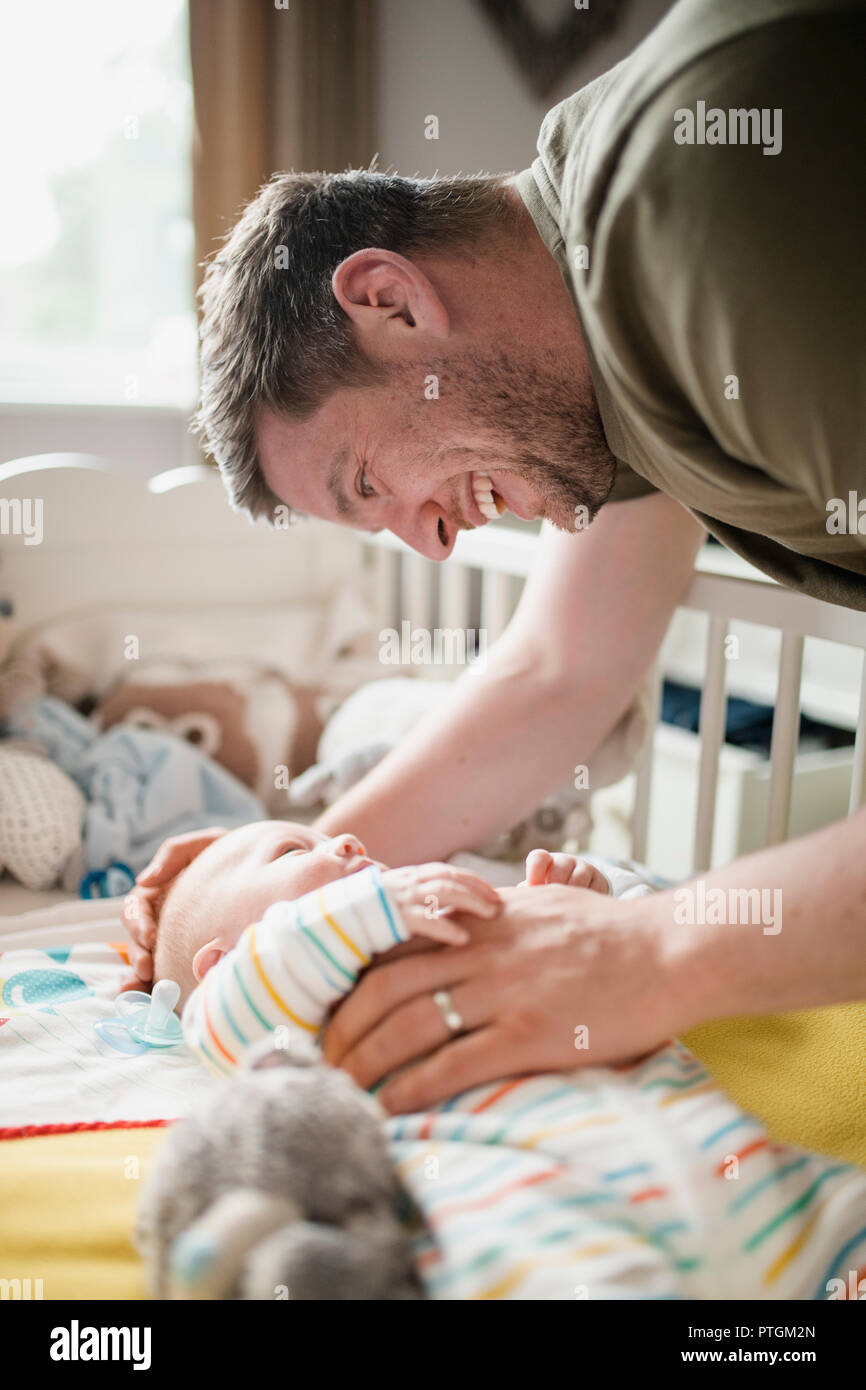 Mitte - Erwachsene Vater überprüfung oben auf sein neugeborenes Baby Boy, während er in der Krippe liegt. Stockfoto