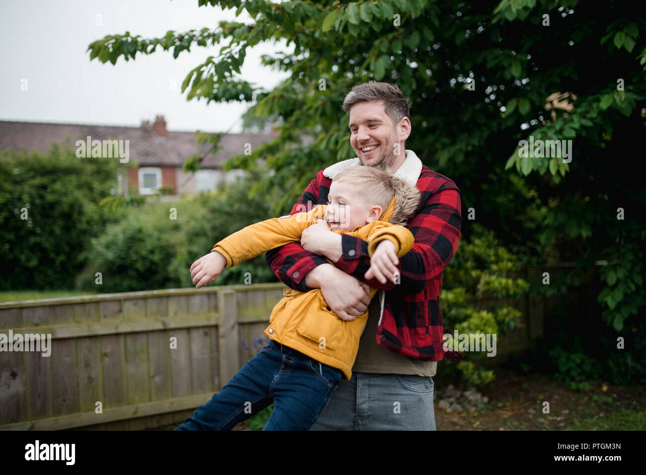 Little boy Spaß mit seinem Vater. Der Vater hält seine Söhne um seinen Oberkörper und ihn Schwingen um beim Lachen und Lächeln. Stockfoto