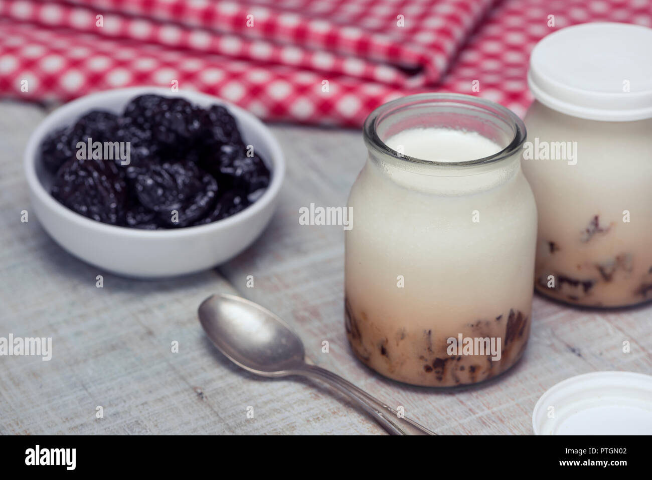 Leckere hausgemachte Joghurt mit gehacktem Pflaumen in Gläsern auf einem weißen Holztisch. Das Konzept der natürlichen und gesunden Frühstück Stockfoto