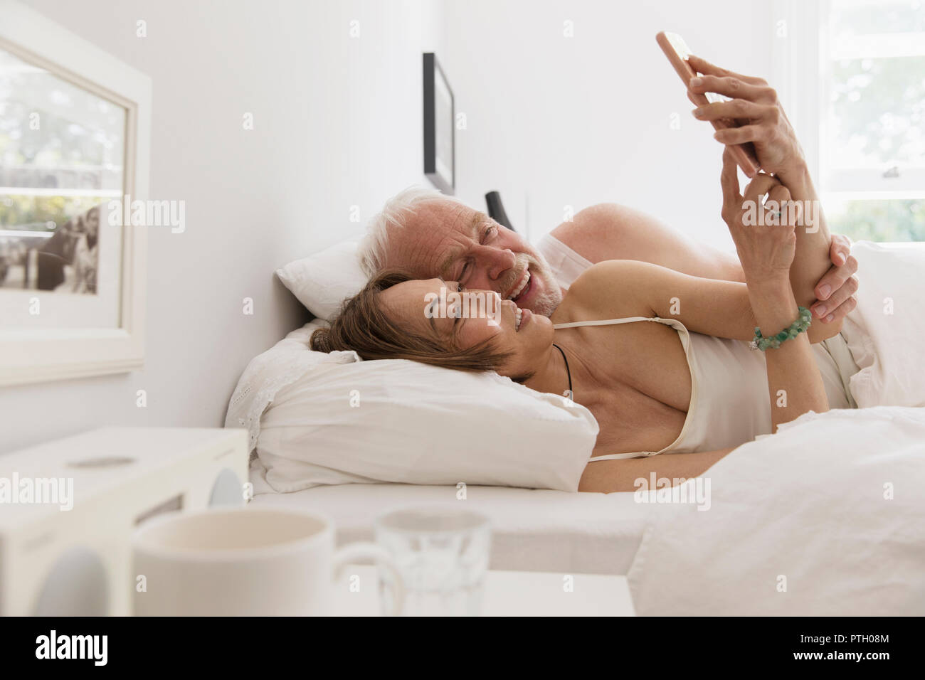 Herzlichen senior Paar mittels Smart Phone im Bett Stockfoto