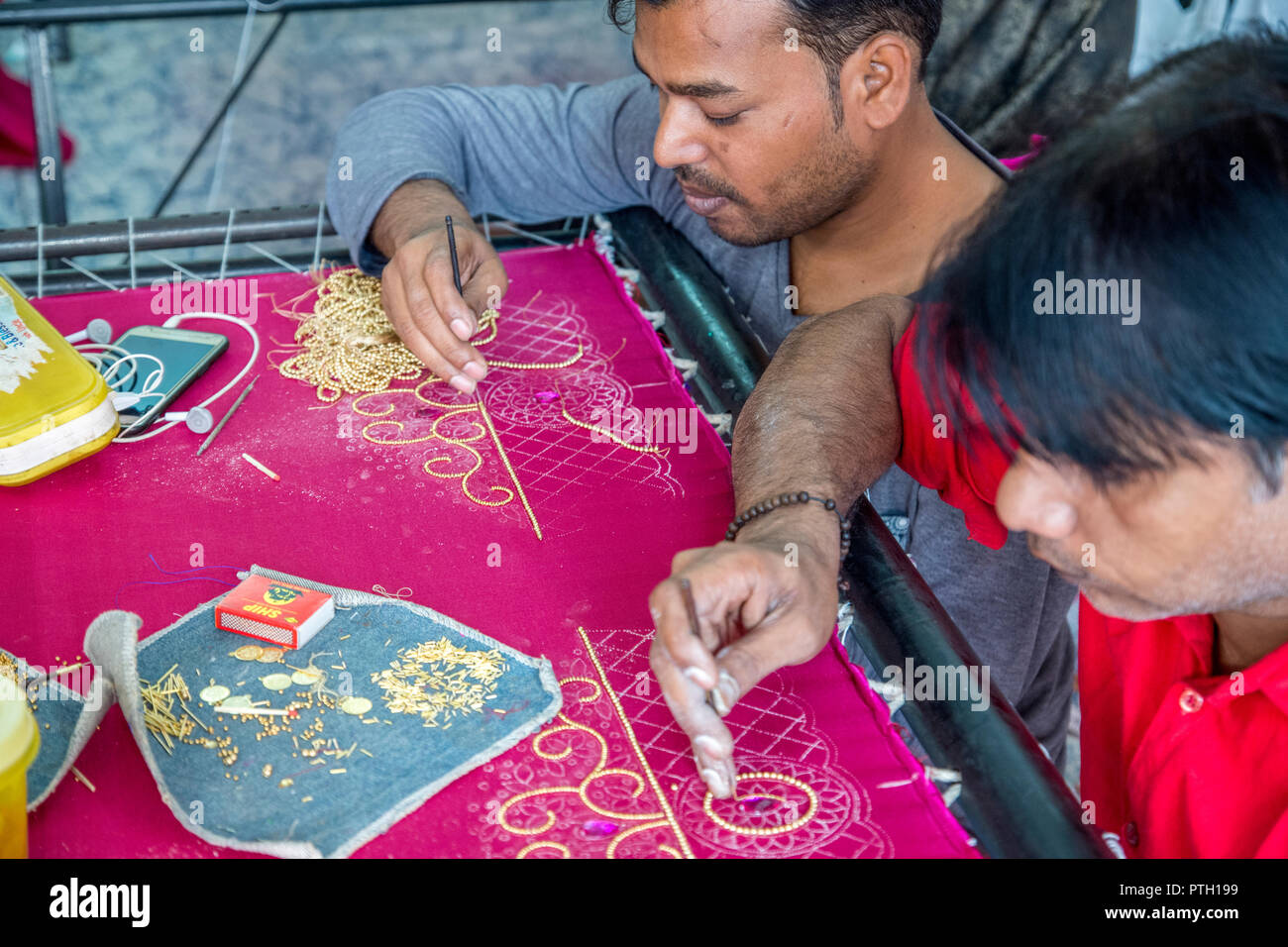 Handwerker, die Stickerei auf einem Sari. In Ahmedabad, Gujarat, Indien fotografierte Stockfoto