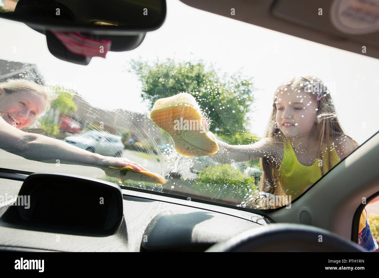 Mutter und Tochter waschen Auto Windschutzscheibe Stockfoto