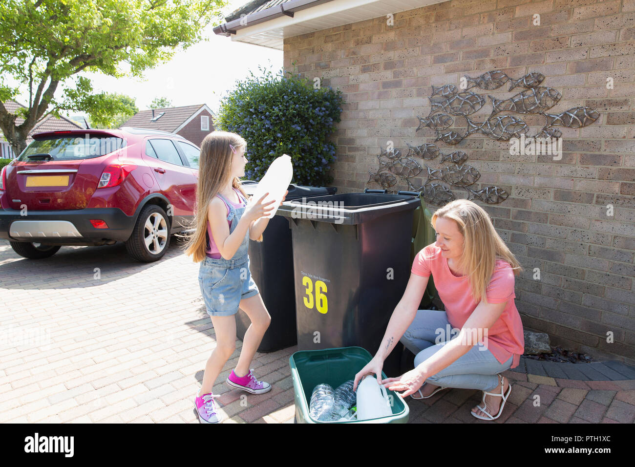 Mutter und Tochter Recycling Kunststoff vor dem Haus Stockfoto