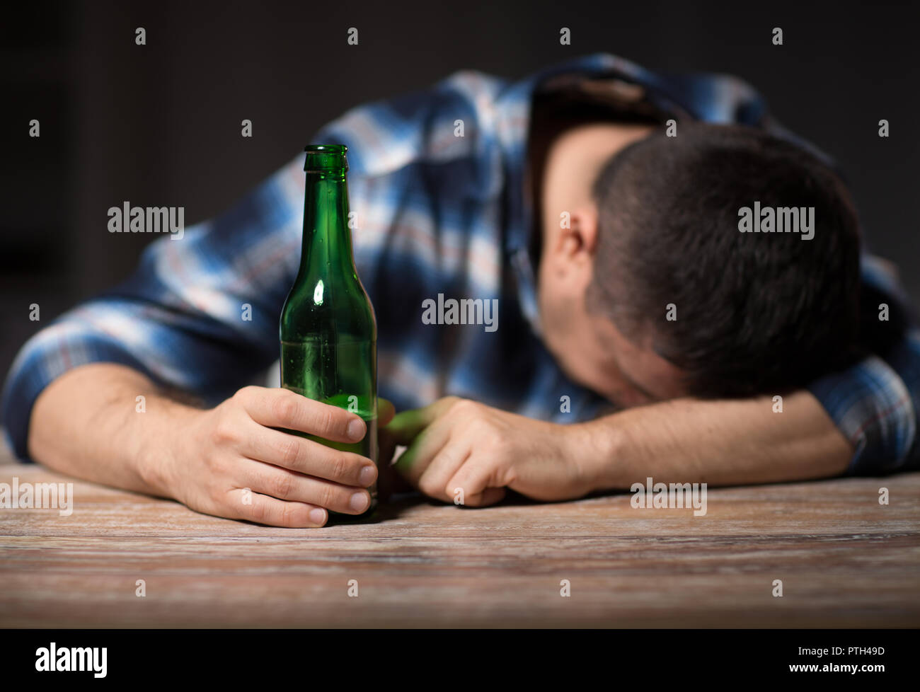 Betrunkener Mann mit Bier Flaschen auf dem Tisch bei Nacht Stockfoto