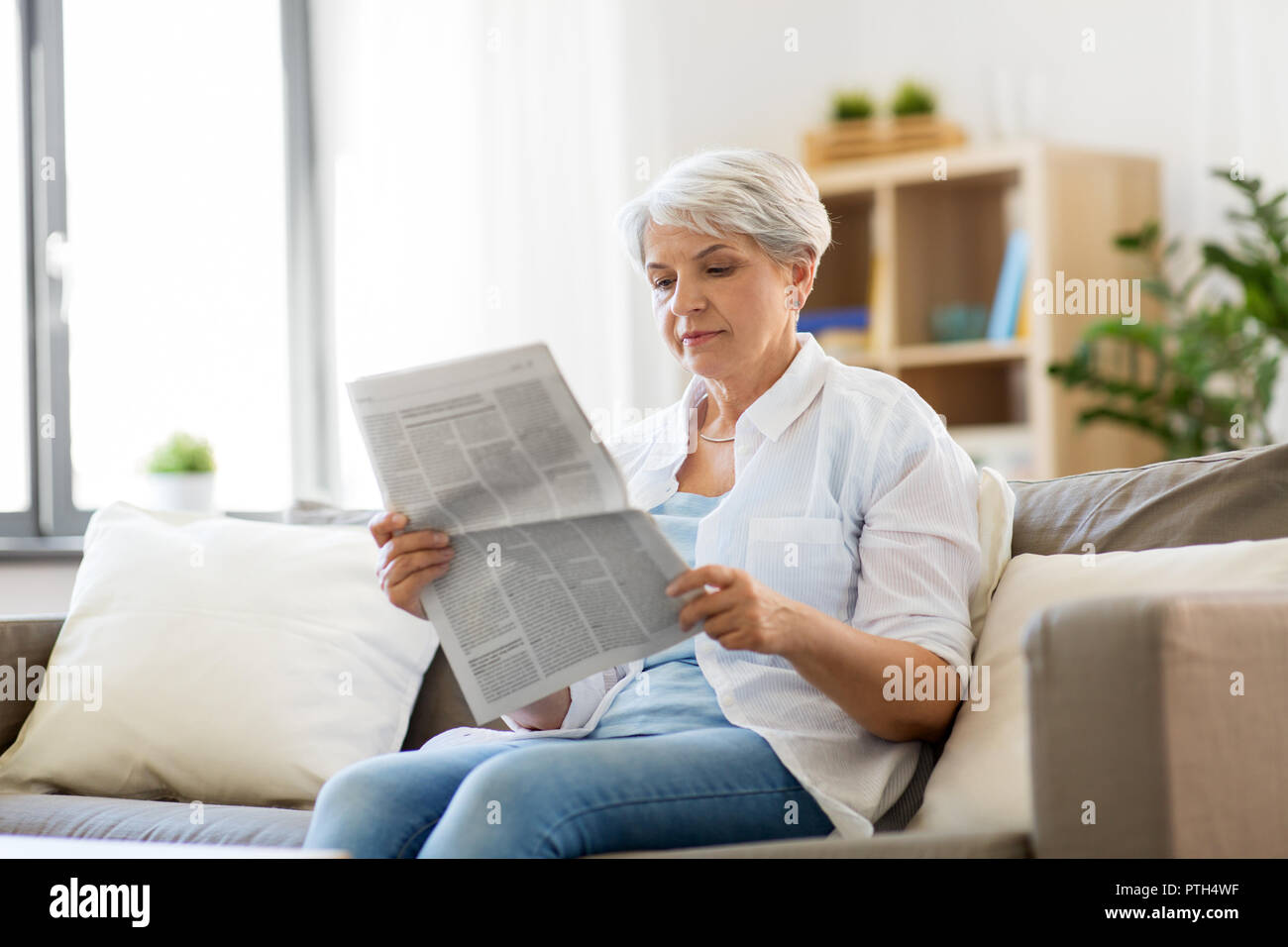 Ältere Frau liest Zeitung zu Hause Stockfoto