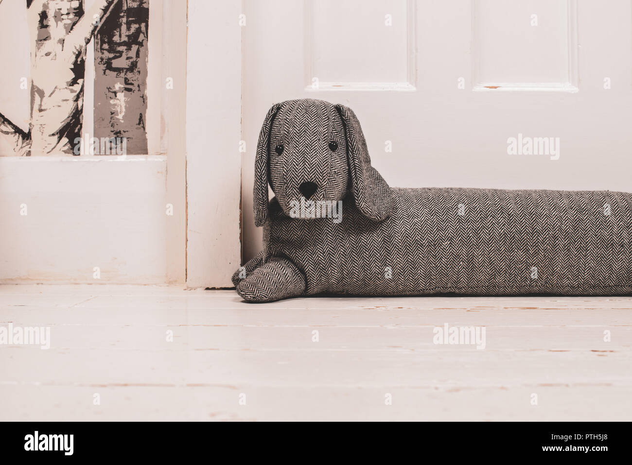 Ein Hund geformte Entwurf Staubdichtung auf einer weiß lackierten Holz- flloor und vor einer Tür. Stockfoto