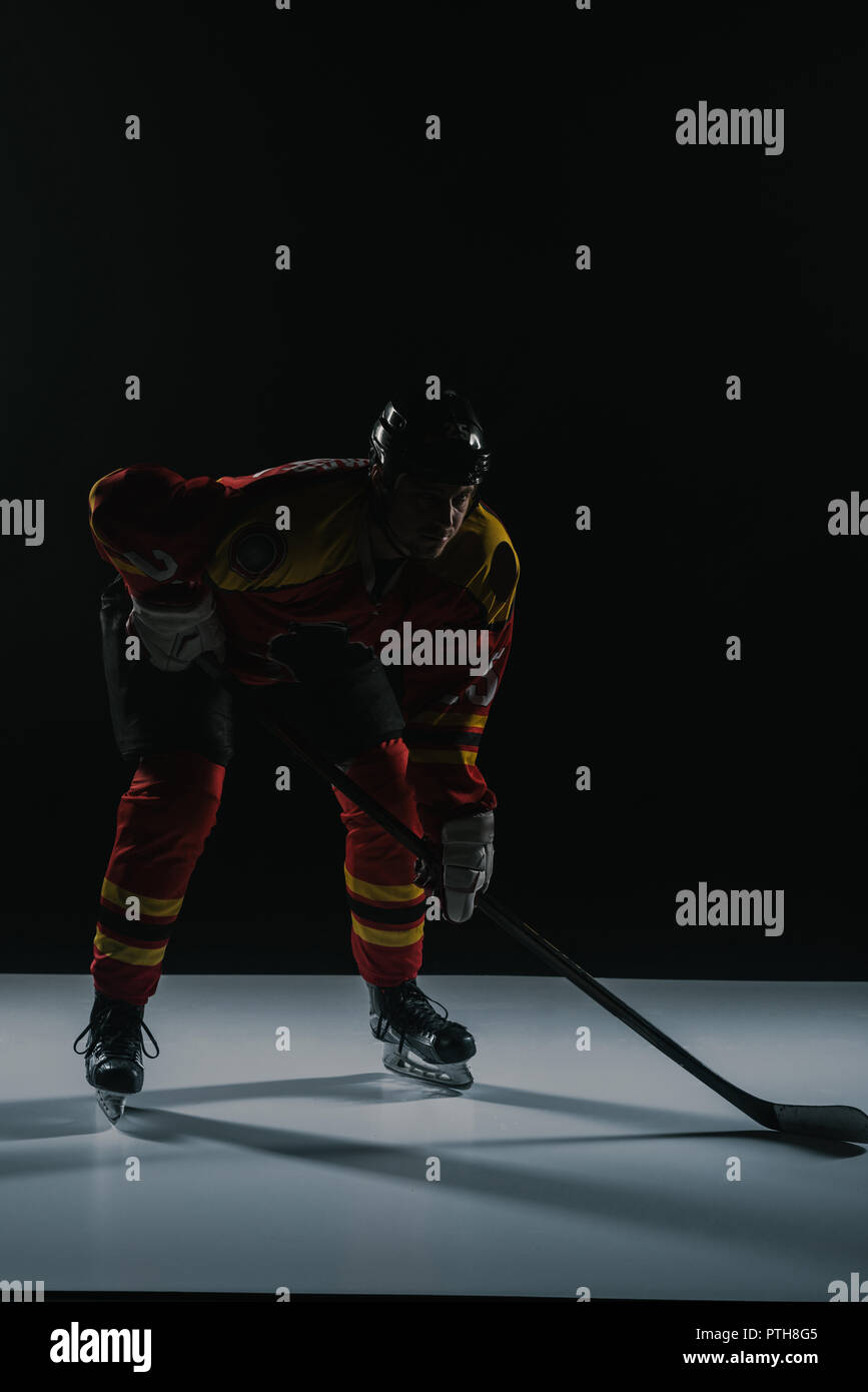 Die volle Länge der Sportsman in sportschutzausrüstungen Eishockey auf Schwarz Stockfoto
