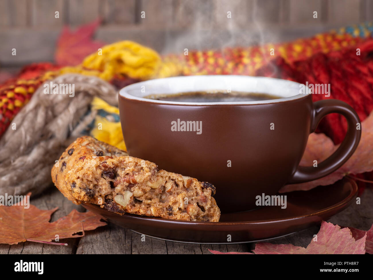Nahaufnahme einer dampfenden Tasse Kaffee und Rosinen Cookies mit Herbst Blätter und bunte Decke im Hintergrund Stockfoto