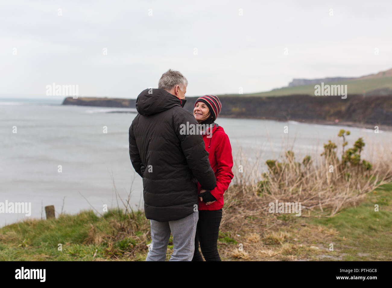 Paar sprechen auf einer Klippe mit Blick auf den Ozean Stockfoto