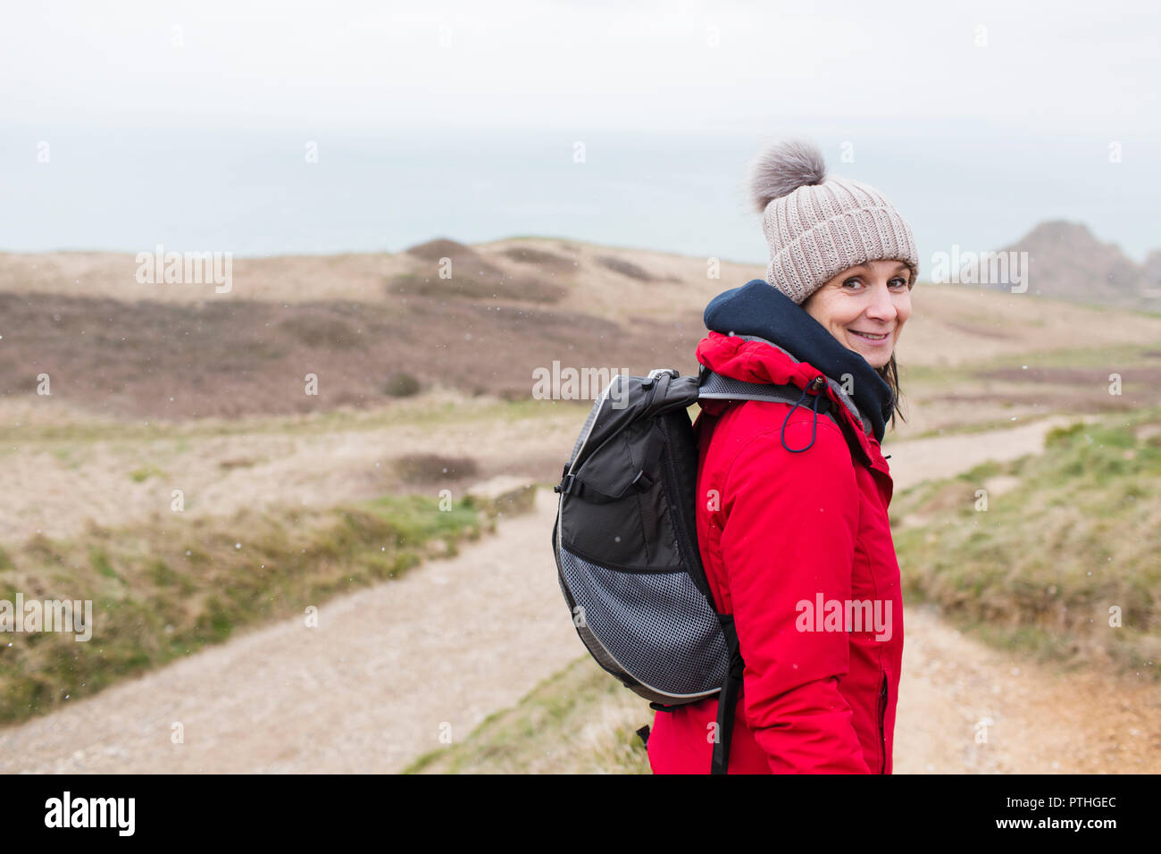 Portrait lächelnde Frau in warme Kleidung mit Rucksack wandern auf Remote-Pfad Stockfoto