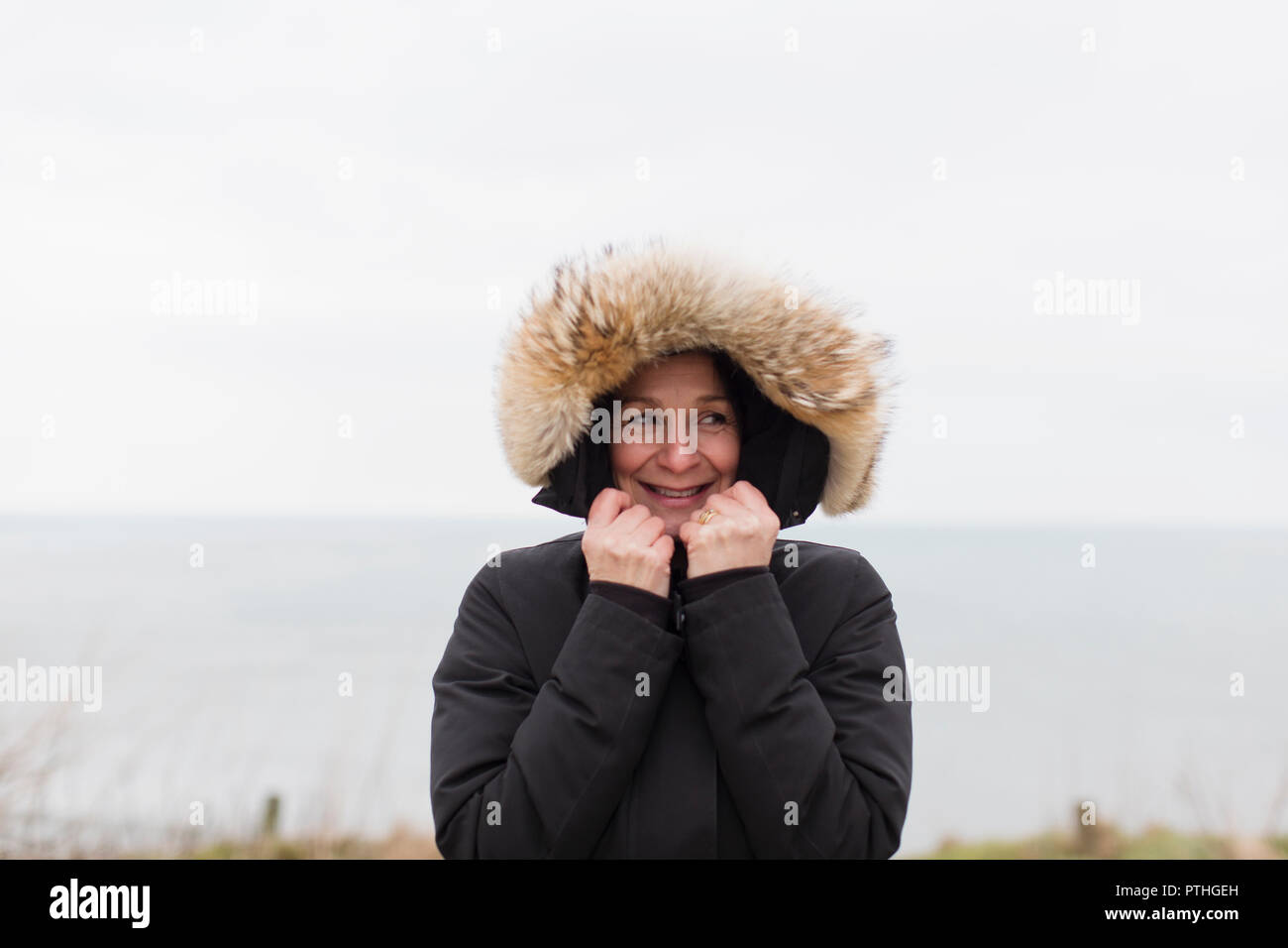 Portrait lächelnde Frau im Mantel mit Fell Kapuze Stockfoto