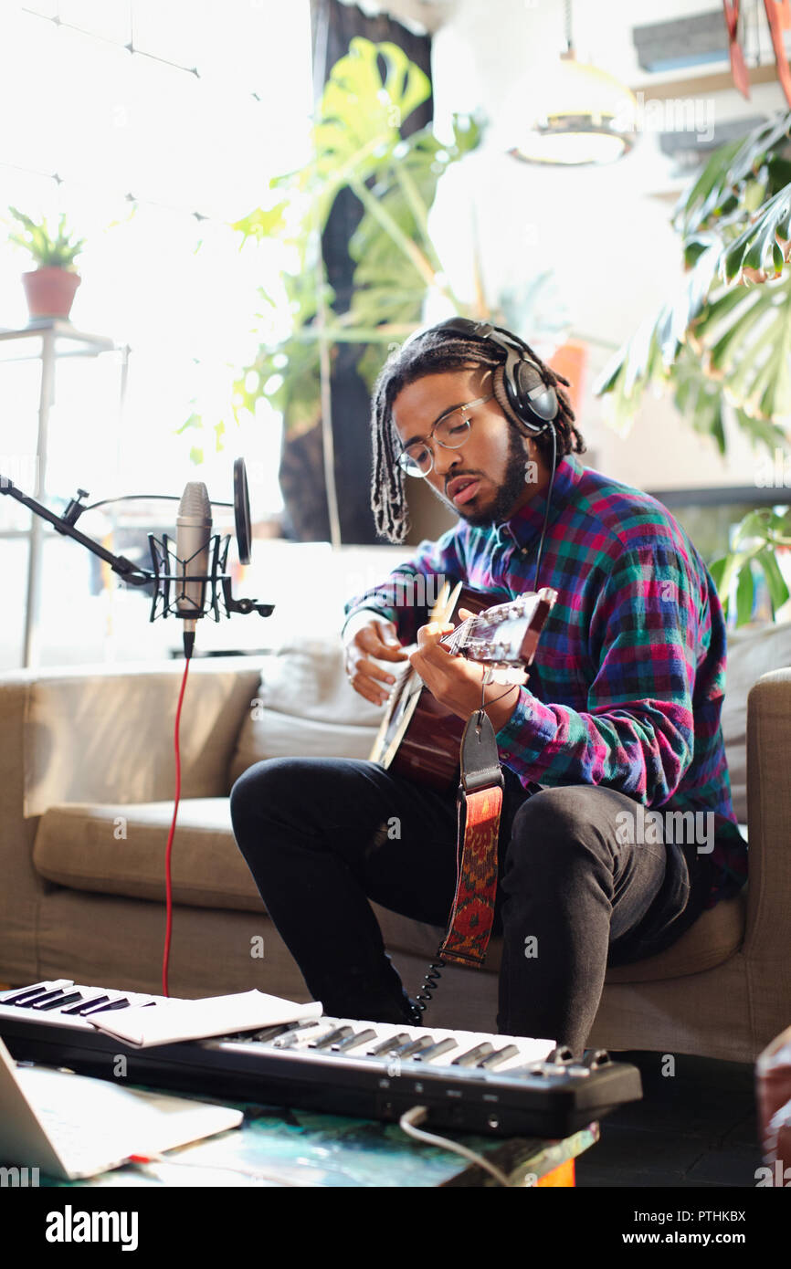 Junger Mann aufnehmen von Musik, Gitarre spielen und singen Sie in das Mikrofon in der Wohnung Stockfoto