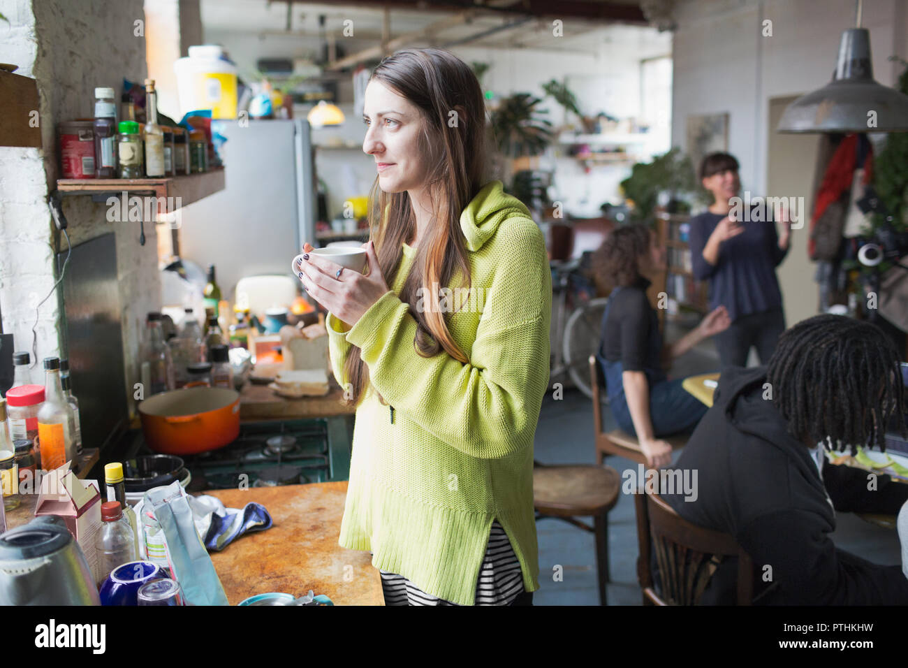 Nachdenkliche junge Frau trinkt Kaffee in der Wohnung Küche Stockfoto