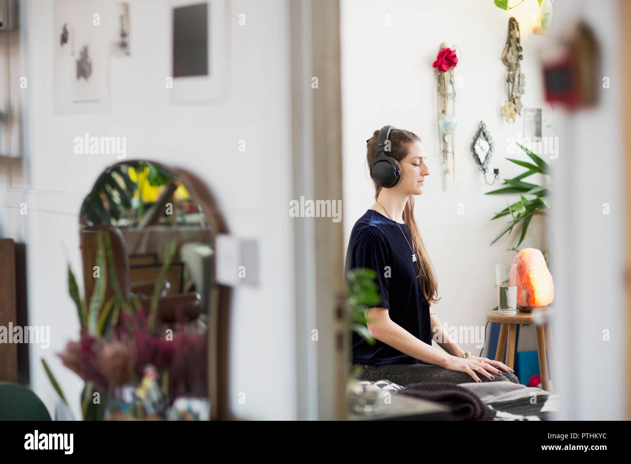Ruhige junge Frau meditieren mit Kopfhörern in der Wohnung Stockfoto