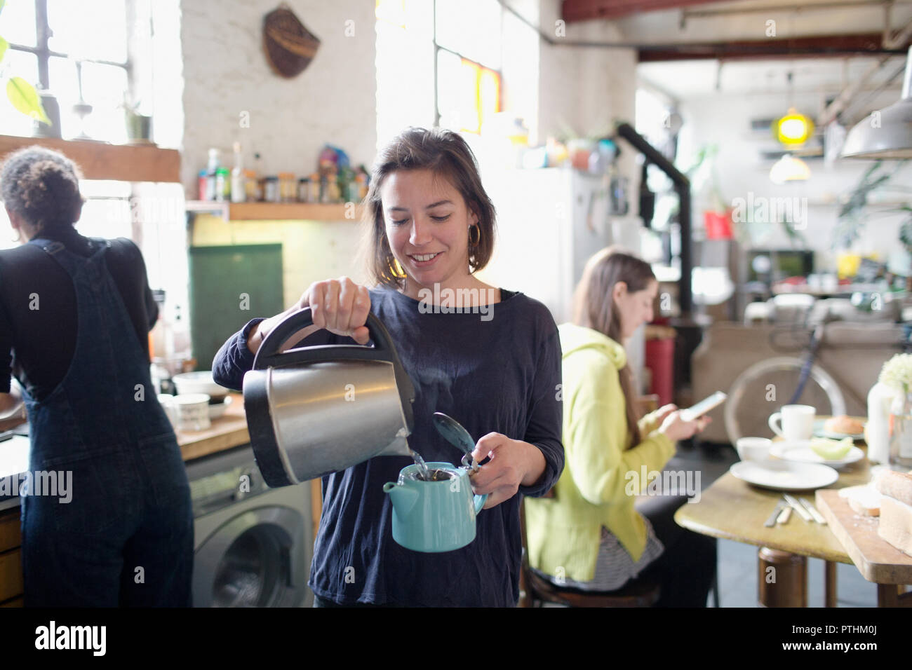 Junge Frau gießen heißes Wasser in die Teekanne in der Wohnung Küche Stockfoto
