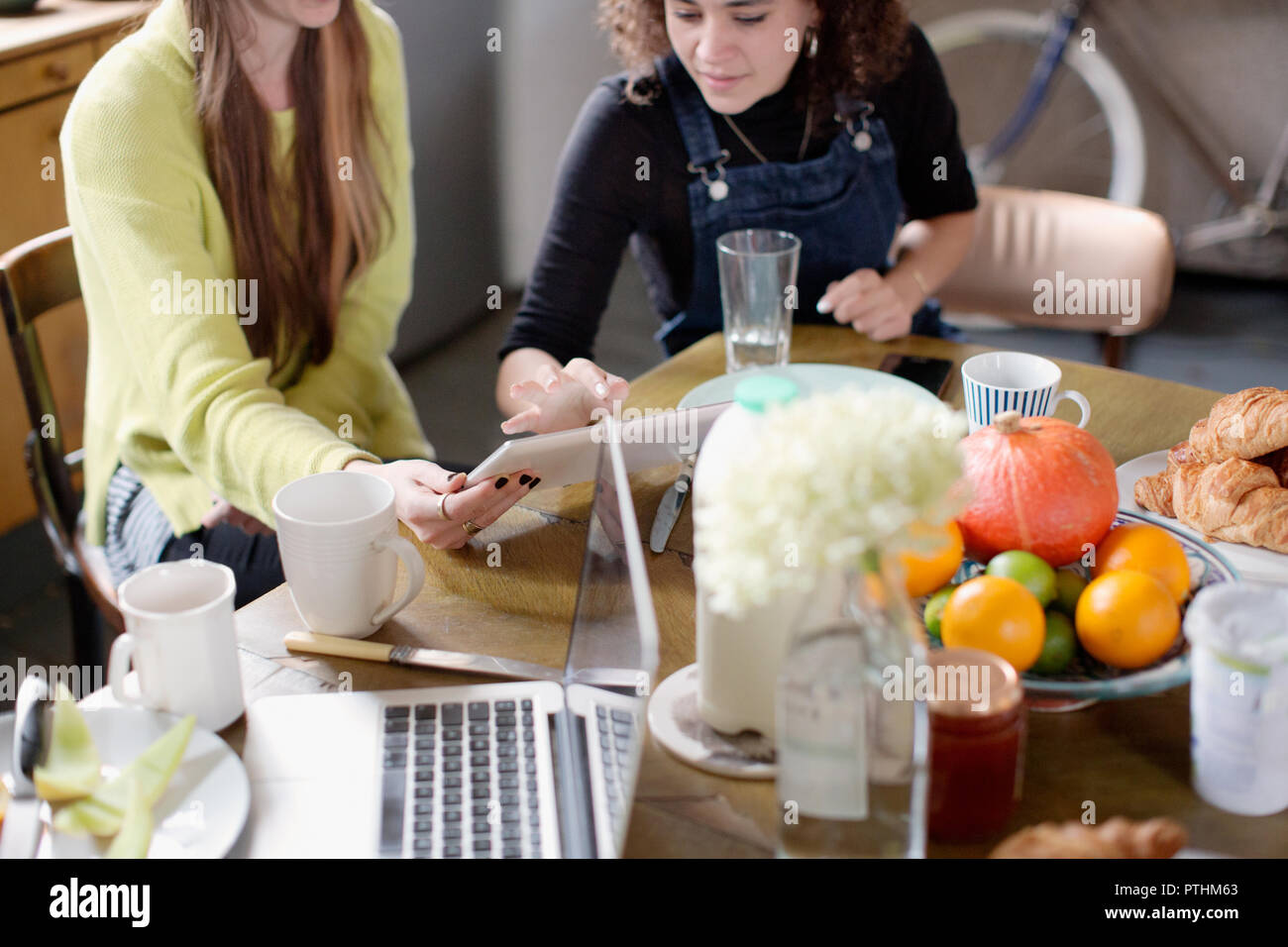 Junge Frauen Mitbewohner Freunde mit digitalen Tablet am Frühstückstisch Stockfoto