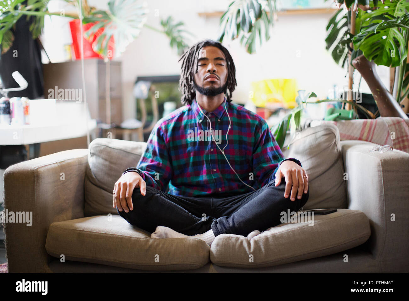 Ruhige junge Menschen meditieren mit Kopfhörern apartment Sofa Stockfoto