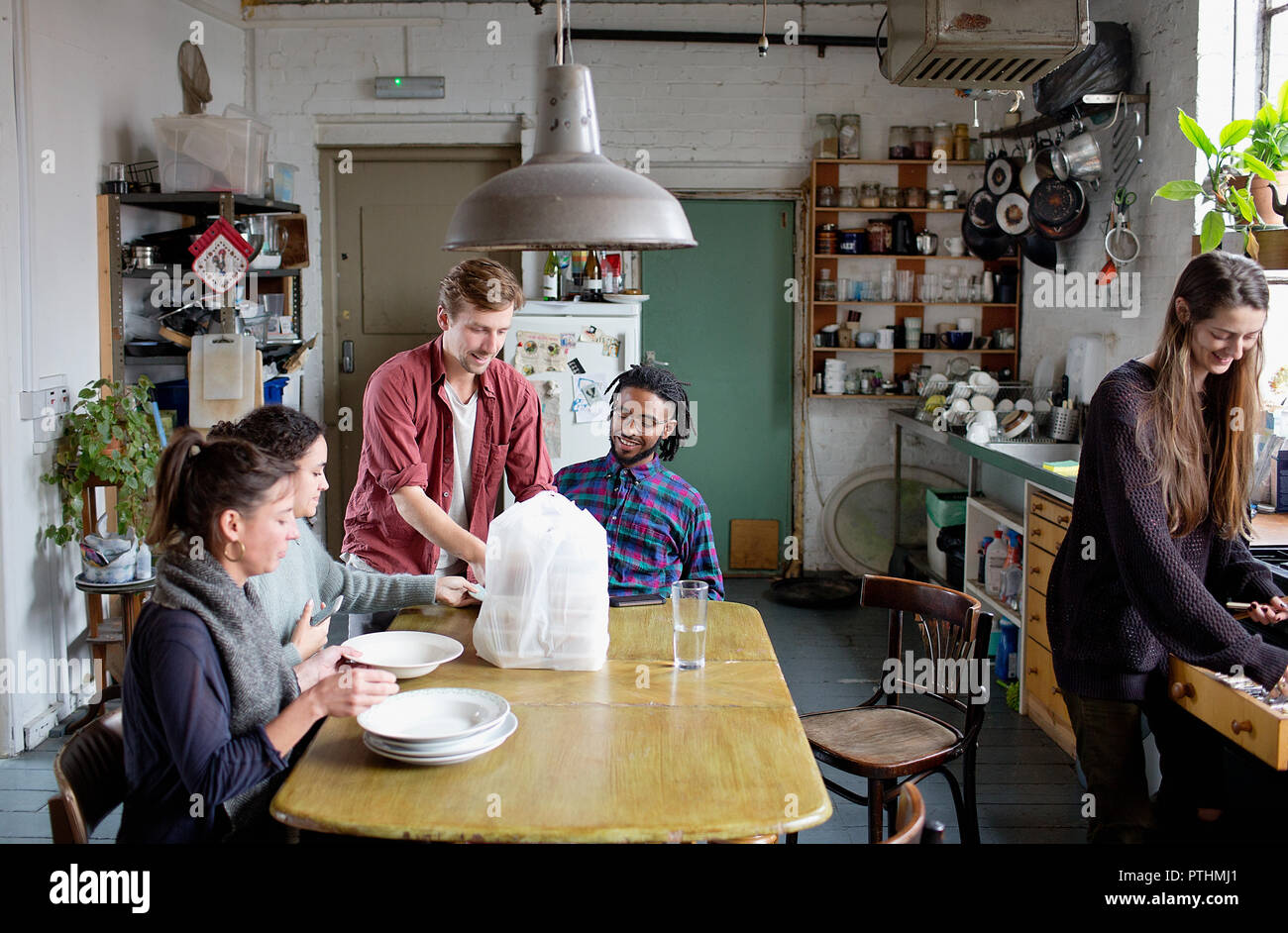 Junge Erwachsene Mitbewohner Freunde Vorbereitung Takeout Essen in der Küche zu essen Stockfoto