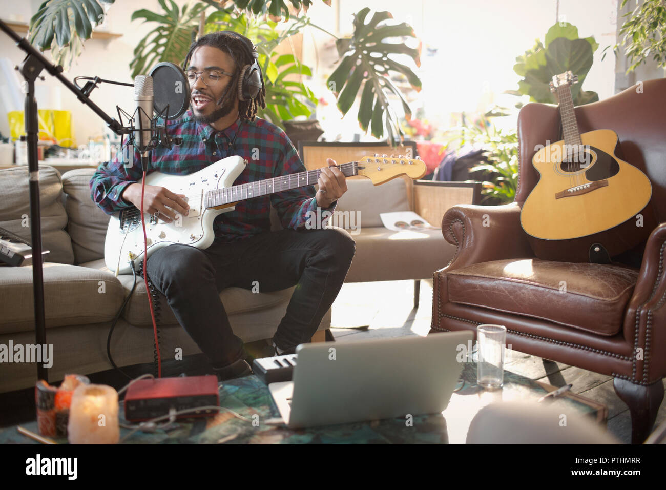 Junge männliche Musiker Aufnehmen von Musik, Gitarre spielen und singen Sie in das Mikrofon in der Wohnung Stockfoto
