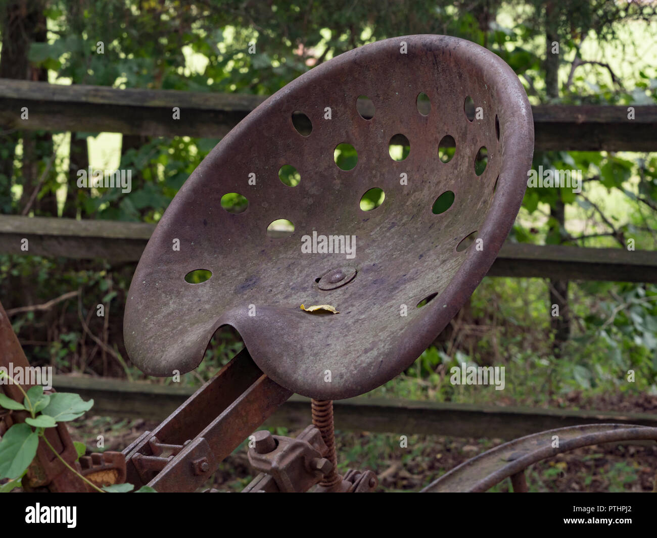 Rusty, antike Farm Equipment Sitz mit split Schiene Zaun im Hintergrund Stockfoto