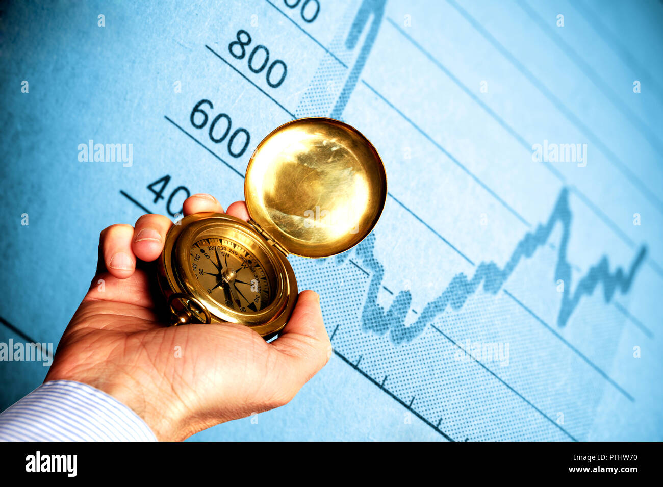 Hand mit einem Kompass vor einem finanziellen Graph, Investitionsentscheidungen und finanziellen Entscheidungen Konzept Stockfoto