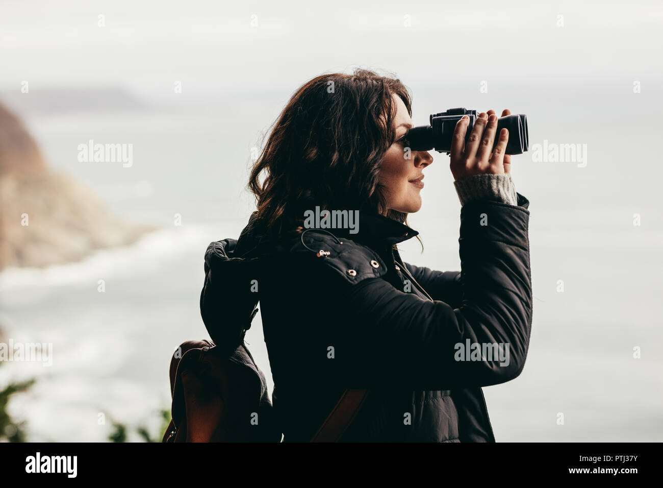 Seitenansicht der weiblichen Wanderer in Ferngläser mit spektakulären Blick vom Berg suchen. Frau tragen warme Jacke Blick durch ein Fernglas. Stockfoto