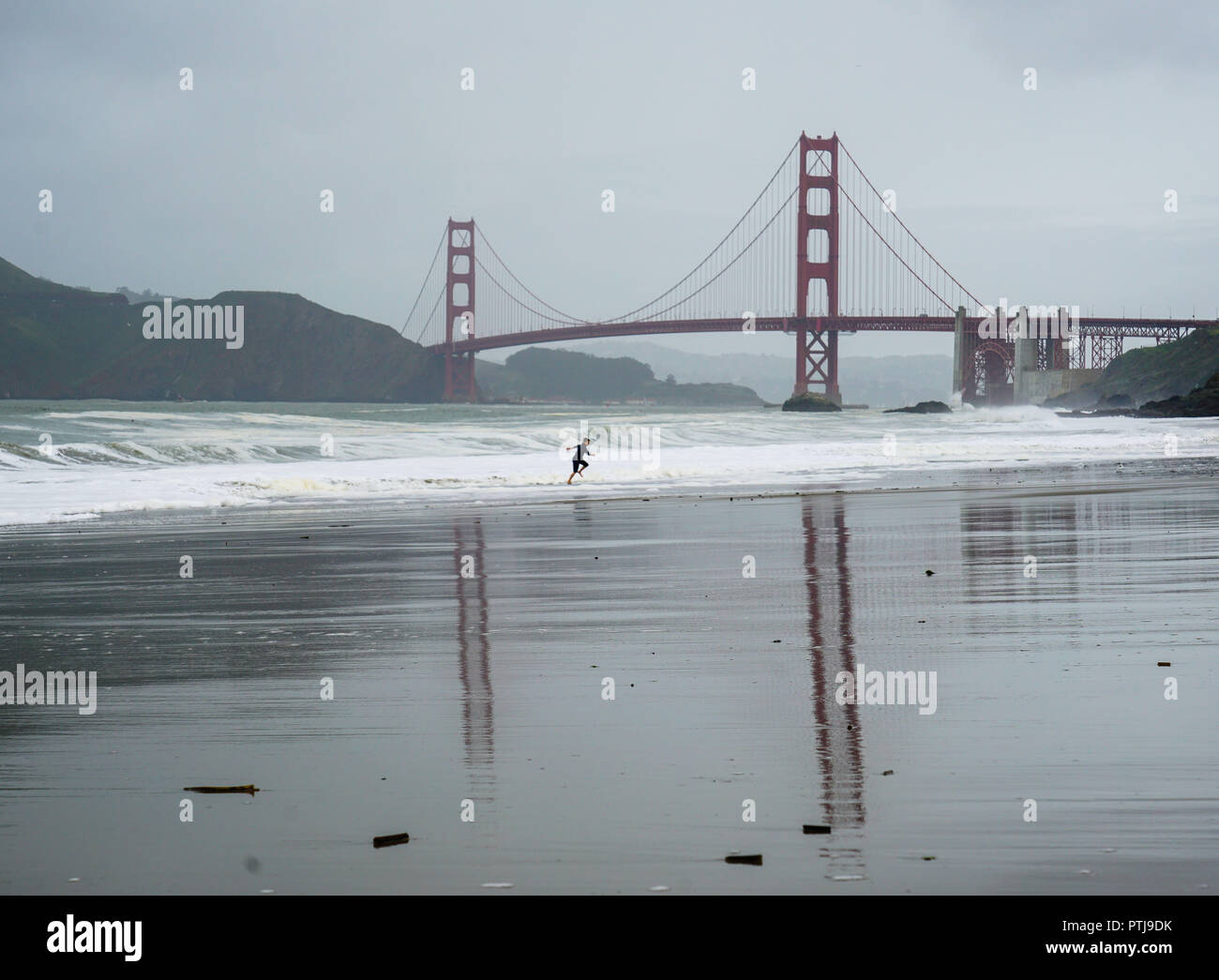 Kleine Figur, die in den Wellen unter der Golden Gate Bridge in San Francisco Stockfoto