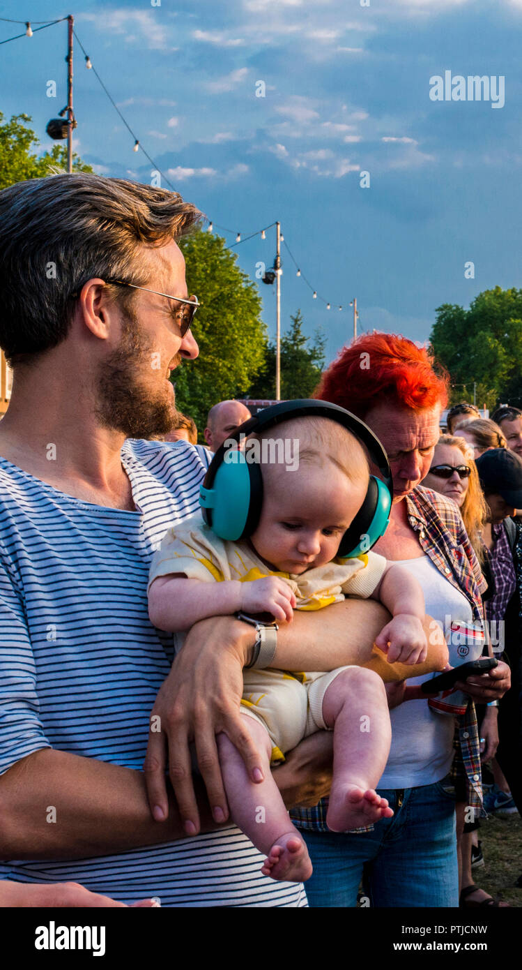 Ein Baby, das Tragen von big blue Kopfhörer ist von seinem Vater an der alle Punkte im Osten Musik Festival in Victoria Park statt. Stockfoto