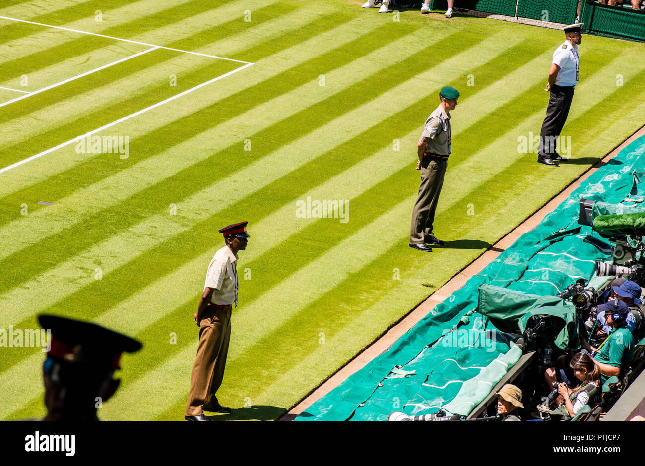 Drei Mitglieder des Militärs tragen verschiedene uniformen geben Sicherheit im Centre Court in Wimbledon Championships, während die Silhouette von einem anderen Offizier im Vordergrund unscharf ist. Stockfoto