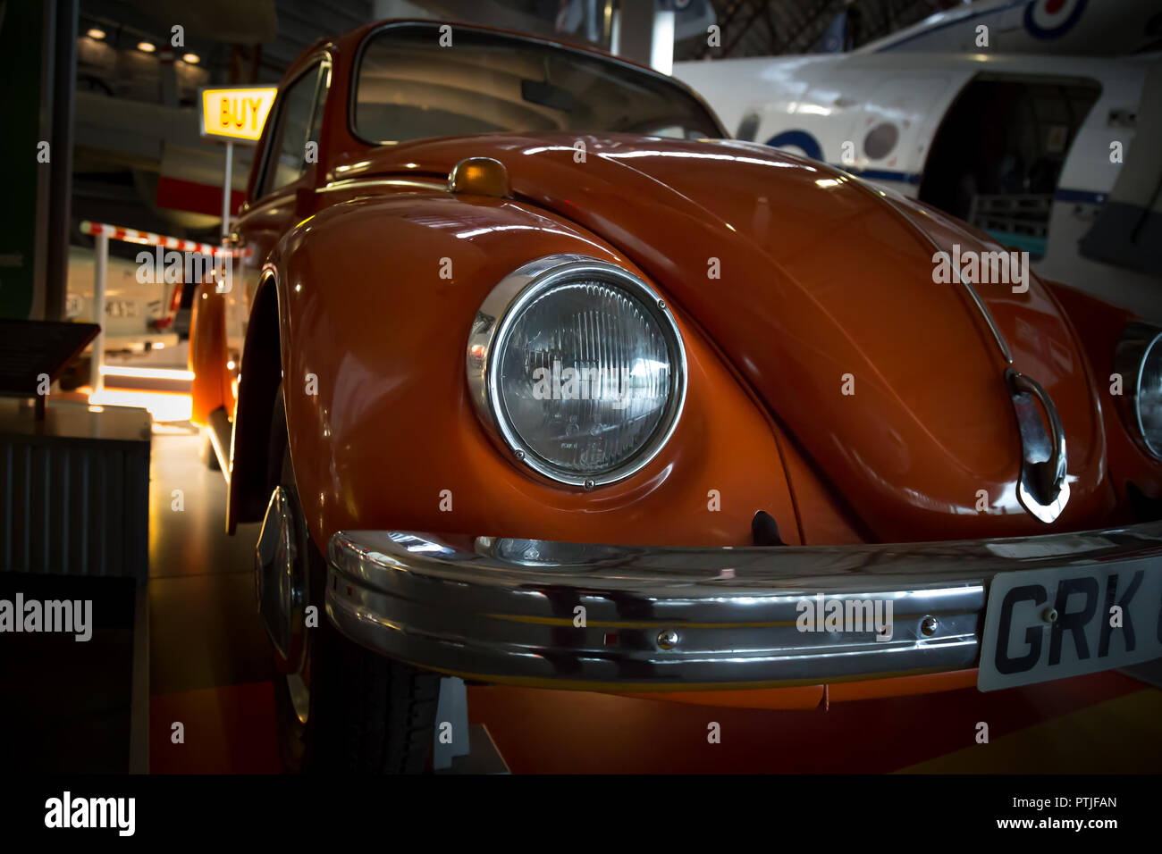 Arty, niedrigen Winkel, Landschaft, Nahaufnahme von gebrannten orange farbiges Volkswagen Käfer, von vorne. Auto steht in Halle. Stockfoto