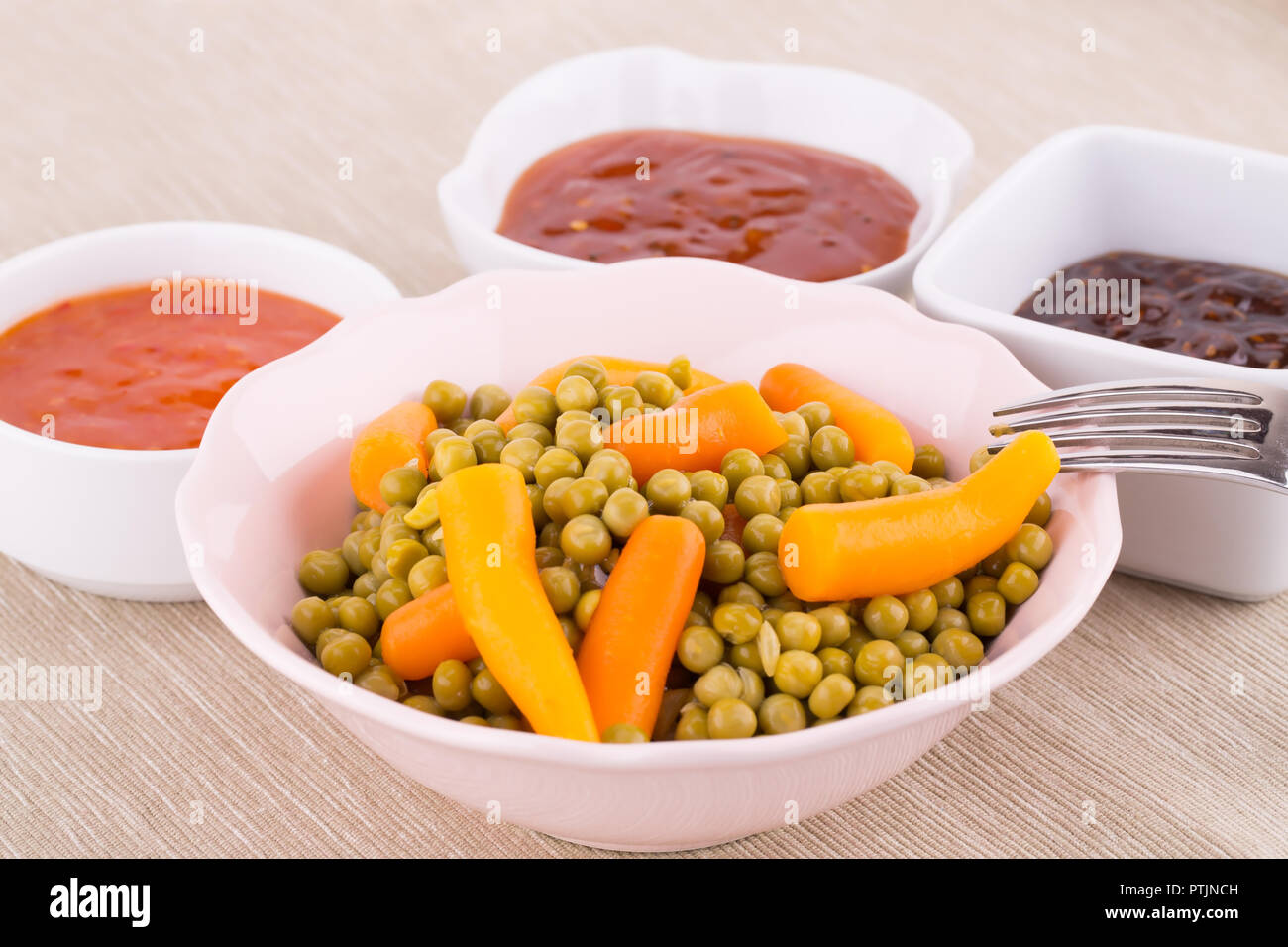 Gekochtes Gemüse und Saucen in Schalen auf beigem Hintergrund Tuch. Stockfoto