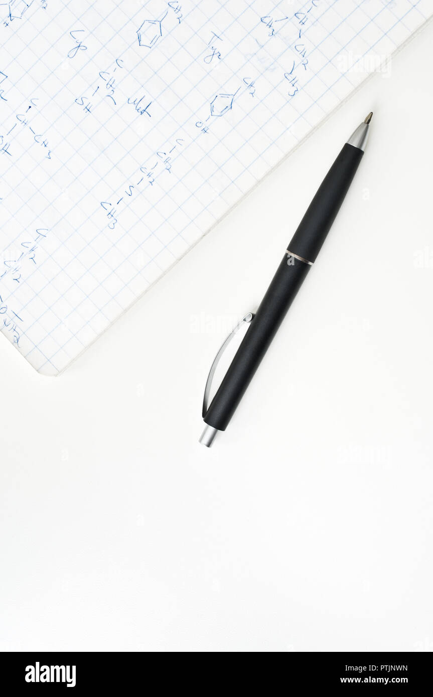 Notebook mit chemischen Formeln und Kugelschreiber auf weißer Tisch. Stockfoto