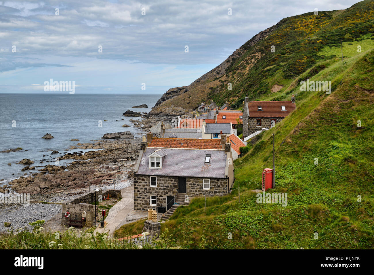 Einzelne Zeile von Häusern der Crovie Küstenfischerei Dorf auf Gamrie Bucht Nordsee Aberdeenshire Schottland Großbritannien mit roten Telefonzelle Stockfoto