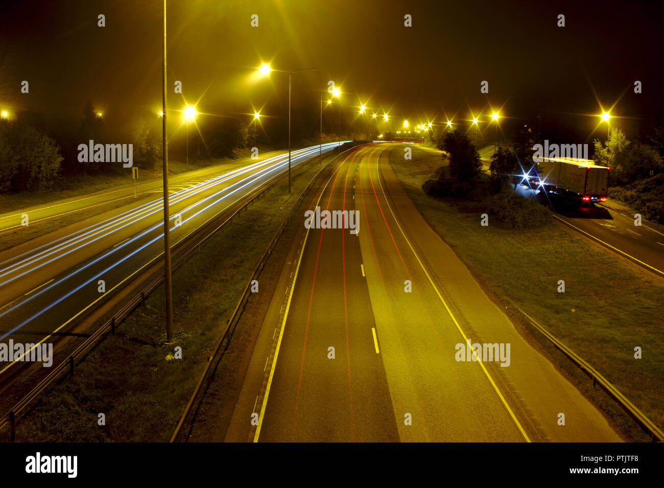 Neblige Nacht auf der Autobahn mit einigen Autos vorbei, leichte Wanderwege. Stockfoto