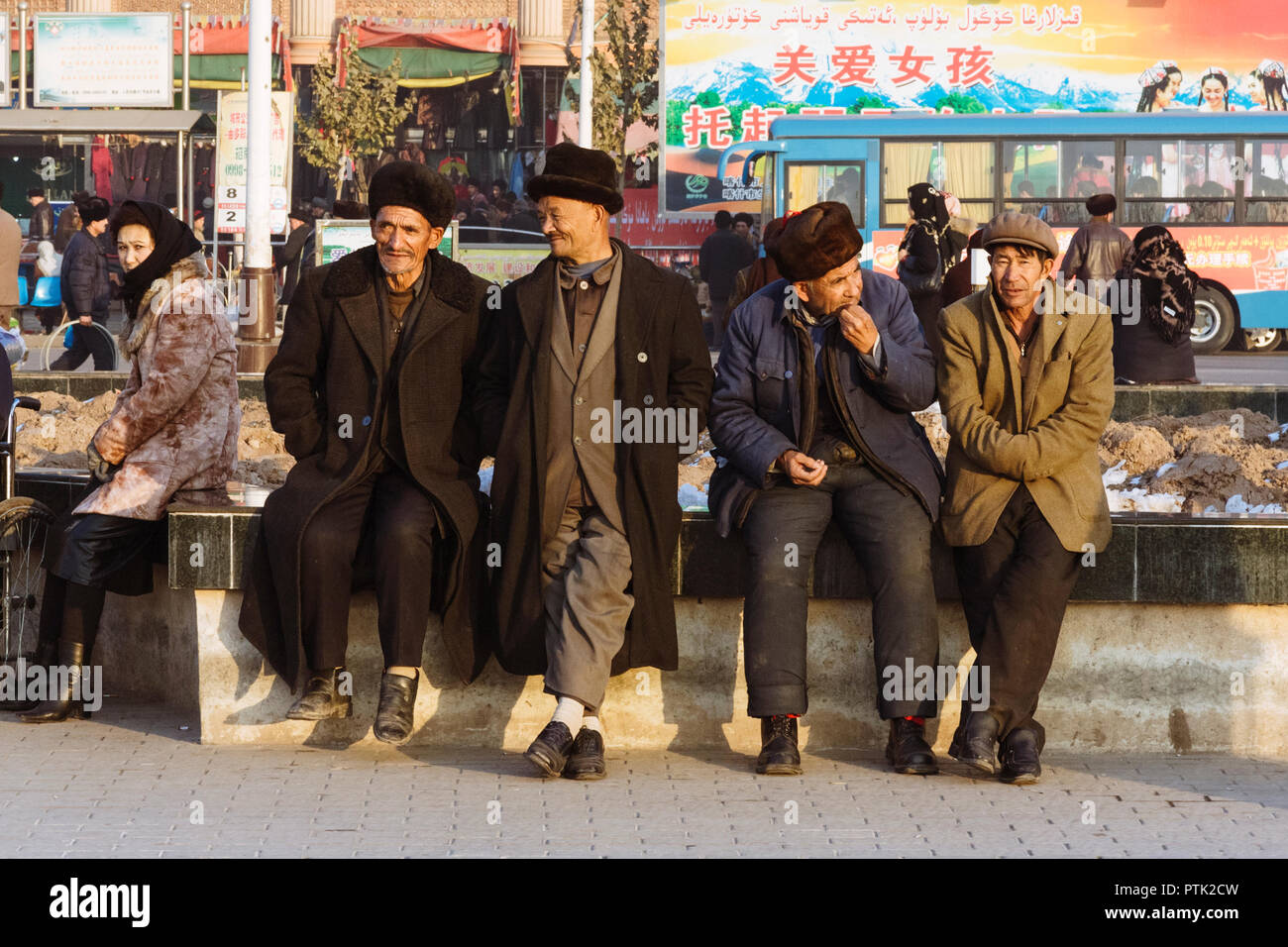 Kashgar, Xinjiang, China: Uiguren Männer sitzen und plaudern an der Straße in Kashgar. Stockfoto