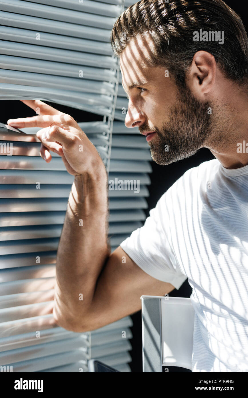 Schöner Mann im weißen T-Shirt mit Bart im Fenster suchen Stockfoto