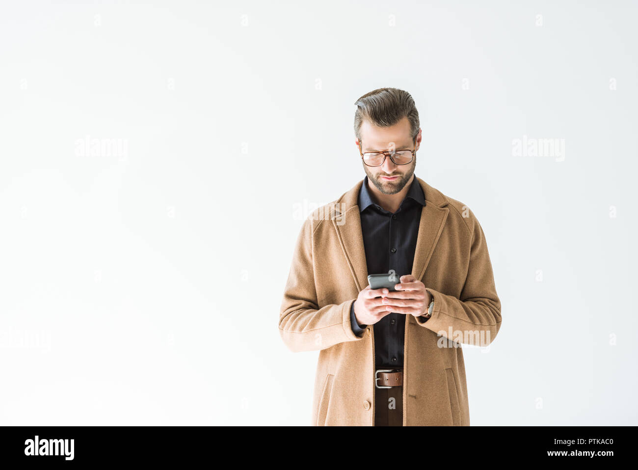 Schöner Mann in Braun mit Smartphone Mantel, isoliert auf weißem Stockfoto