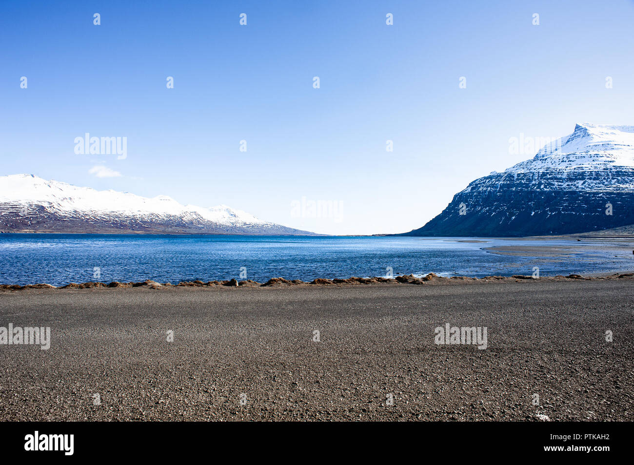 Seydisfjördur, Ostfjorde, Island. Die schneebedeckten Berggipfel, glitzernden Wasser und blauer Himmel Hintergrund Stockfoto