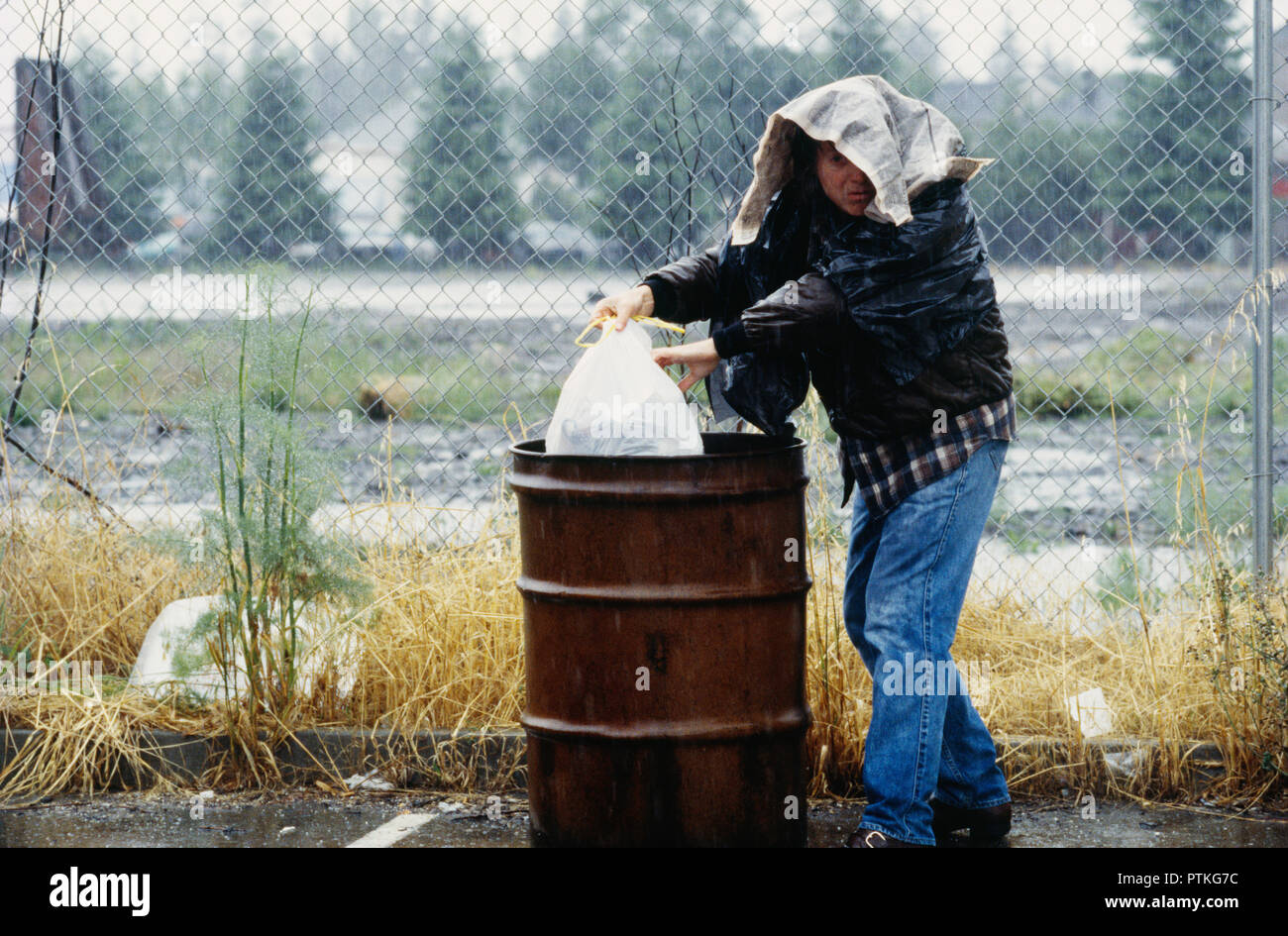 Obdachloser Grabungen durch eine trash Barrel für Lebensmittel, USA Stockfoto