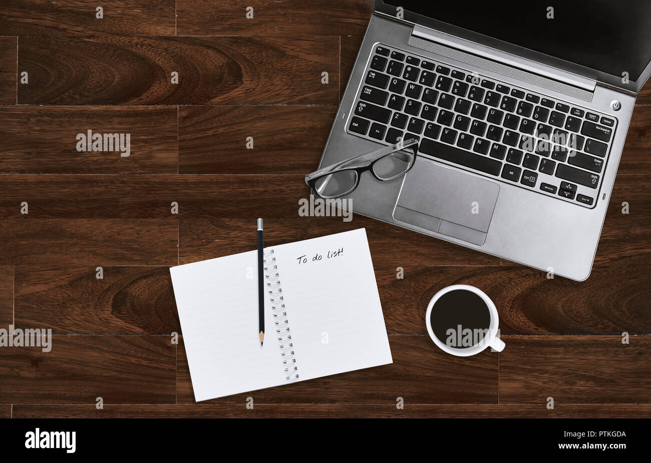 Laptop mit Brillen und öffnen Notebook mit leeren Seite der Aufgabenliste auf hölzernen Tisch Hintergrund mit kopieren. Business Office Schreibtisch Konzept. Nach oben V Stockfoto