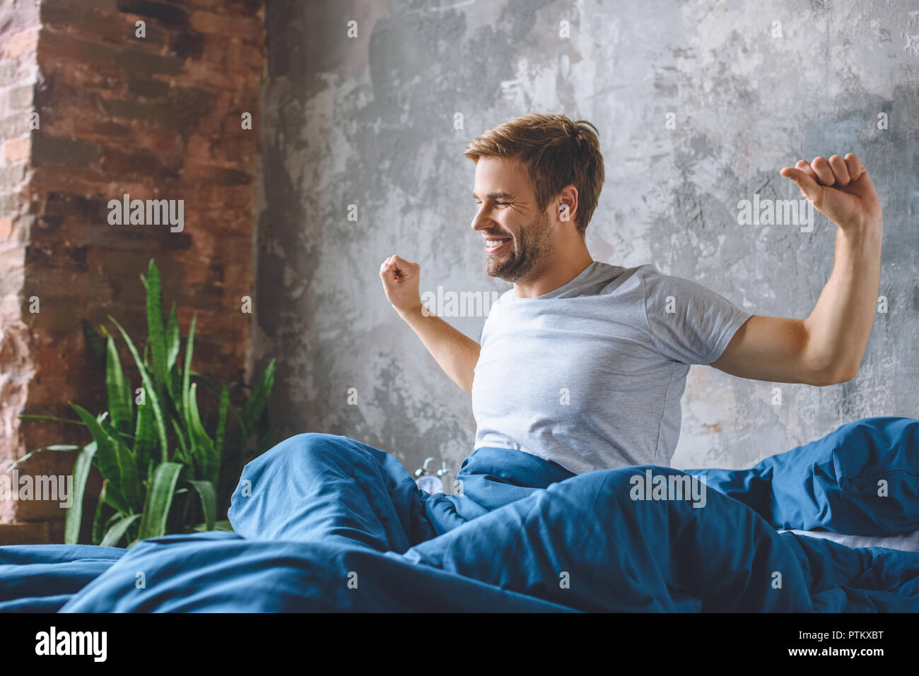 Hübscher junger Mann Stretching im Bett während der Morgen Zeit zu Hause Stockfoto
