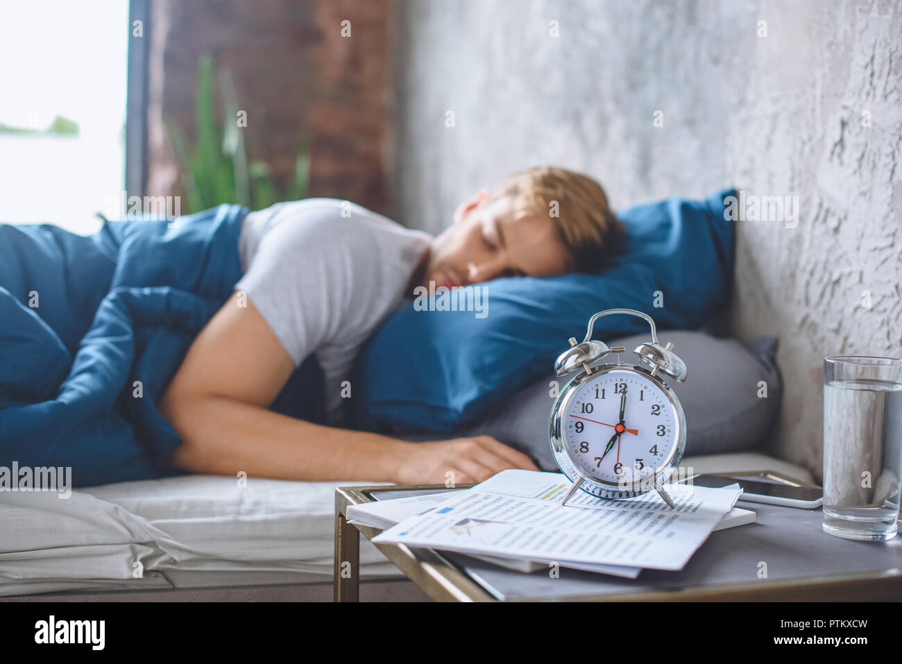 Selektiver Fokus der Wecker und schlafenden Mann im Bett hinter Stockfoto