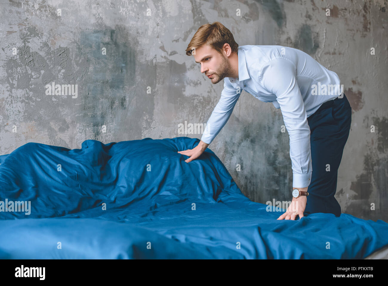 Konzentrierte Geschäftsmann für Bett durch blaue Bettdecke zu Hause Stockfoto