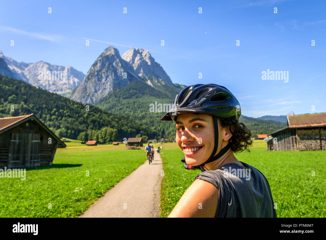 Weibliche Radfahrer mit Helm auf dem Fahrrad tour, in der Rückseite Zugspitze, Tegernauweg, in der Nähe von Grainau, die Alpen Stockfoto