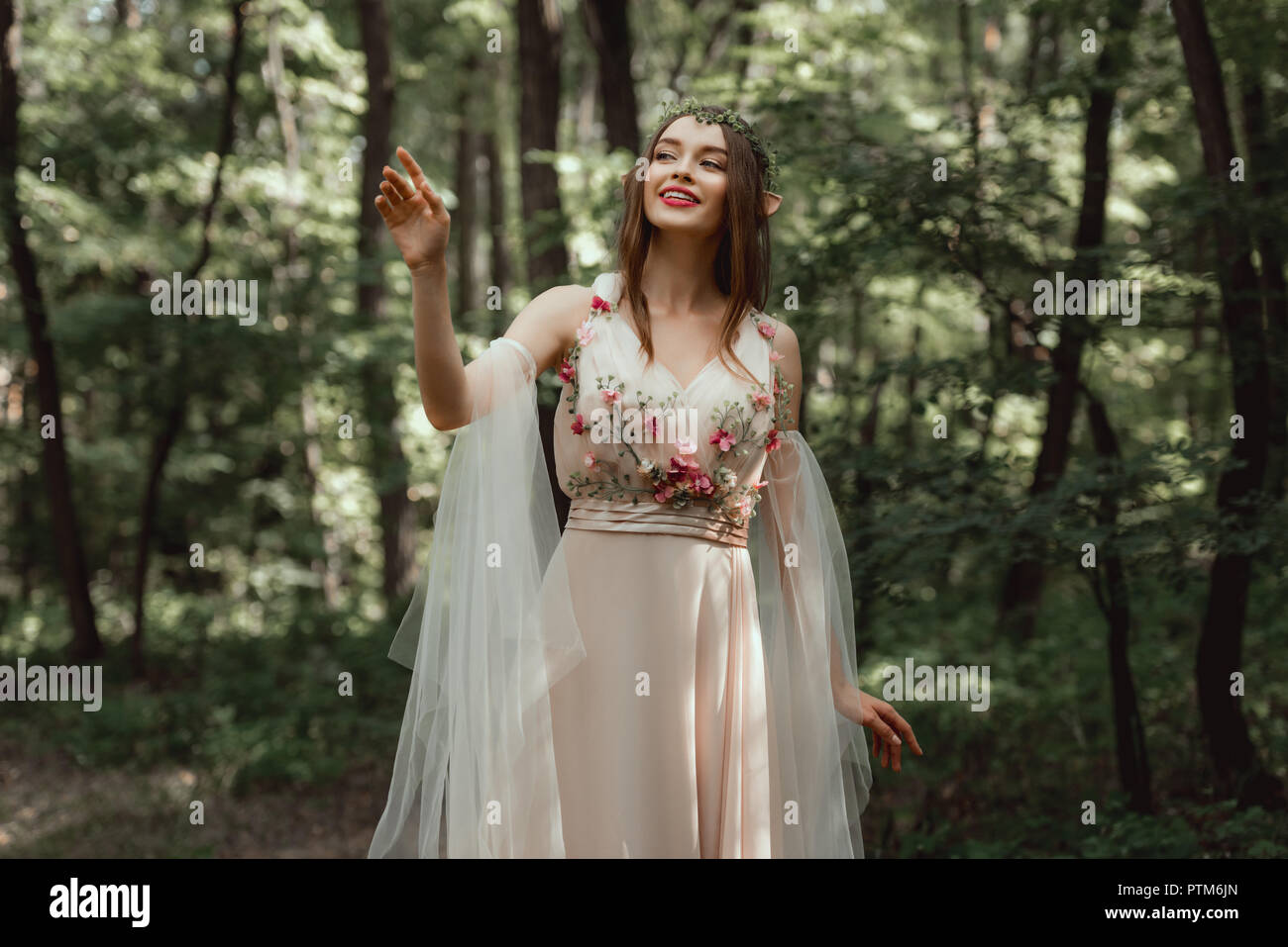 Happy elf Mädchen in elegantes Kleid mit Blumen im Wald Stockfoto