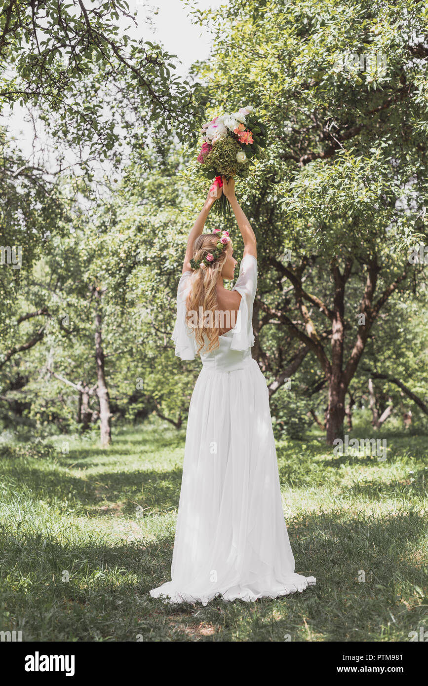 Ansicht der Rückseite des schönen jungen Braut im Brautkleid werfen Blumenstrauß in Park Stockfoto